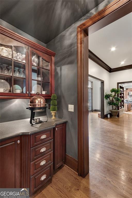 bar with crown molding and light hardwood / wood-style flooring