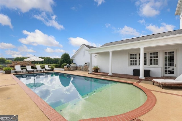 view of pool with area for grilling and a patio