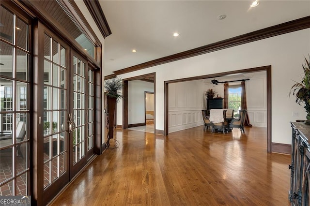 hallway with french doors, ornamental molding, and light hardwood / wood-style floors