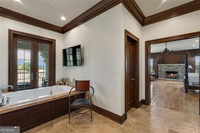 bathroom featuring ceiling fan, french doors, a stone fireplace, and ornamental molding