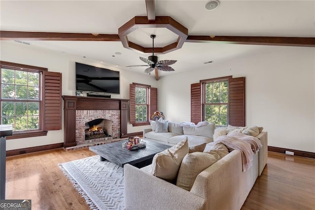 living room with a brick fireplace, ceiling fan, and light wood-type flooring