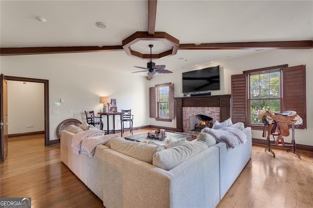 living room with a brick fireplace, hardwood / wood-style flooring, lofted ceiling with beams, and ceiling fan