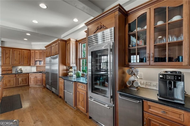 kitchen with light hardwood / wood-style floors, stainless steel built in refrigerator, dark stone counters, and high end fridge