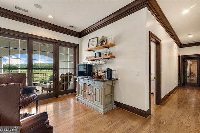 interior space featuring light wood-type flooring, french doors, and ornamental molding