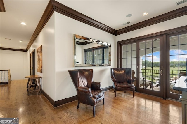 living area with hardwood / wood-style floors and crown molding