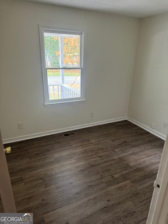 empty room featuring a textured ceiling and dark hardwood / wood-style floors