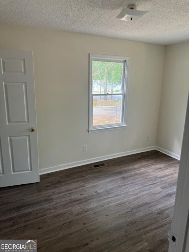 spare room featuring dark hardwood / wood-style flooring and a textured ceiling