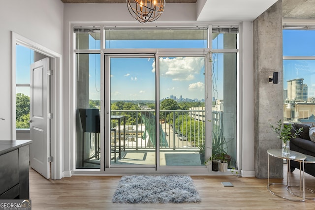 doorway with plenty of natural light, a chandelier, and light wood-type flooring