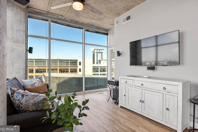 living room featuring ceiling fan, floor to ceiling windows, and light hardwood / wood-style floors