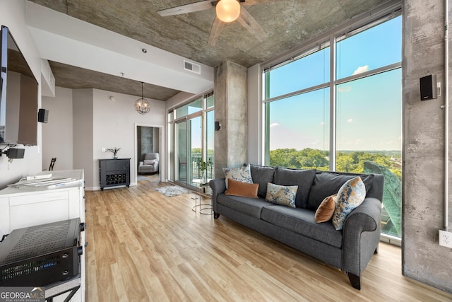 living room featuring ceiling fan with notable chandelier and light wood-type flooring