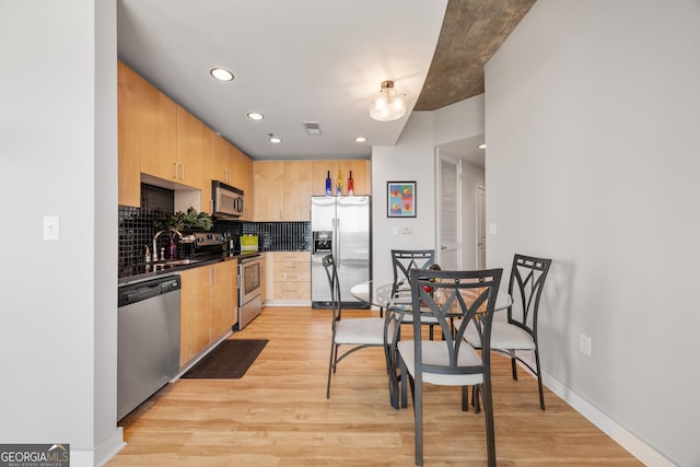 kitchen featuring light brown cabinetry, sink, decorative backsplash, light hardwood / wood-style floors, and stainless steel appliances