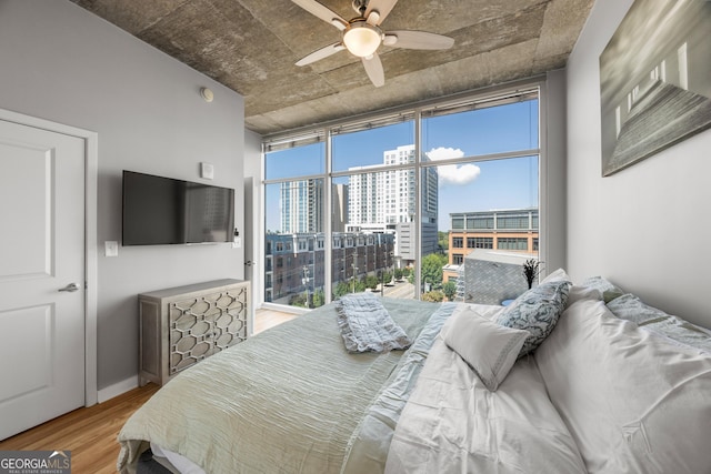 bedroom with a wall of windows, light hardwood / wood-style floors, and ceiling fan