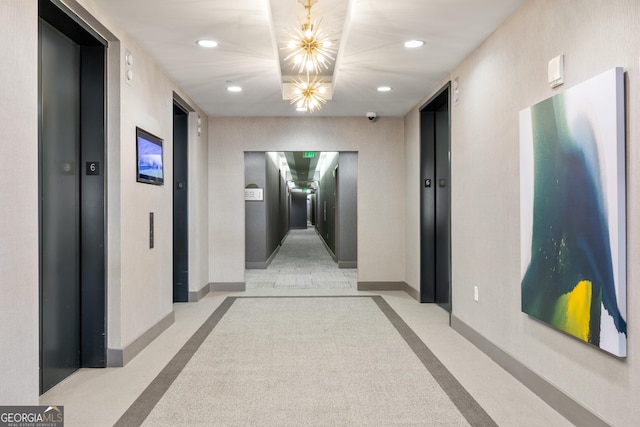 hallway with elevator and an inviting chandelier