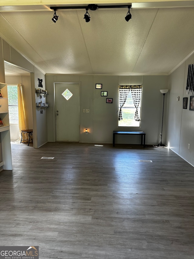 unfurnished living room featuring hardwood / wood-style floors, rail lighting, and a textured ceiling