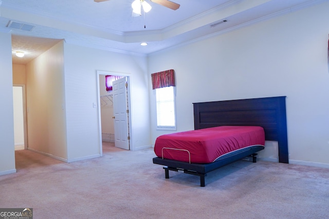 carpeted bedroom featuring a closet, a raised ceiling, crown molding, ceiling fan, and a walk in closet