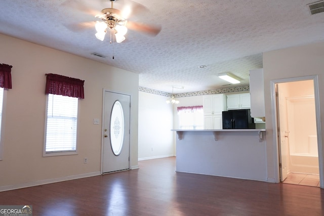 interior space featuring ceiling fan with notable chandelier, dark wood-type flooring, and a textured ceiling