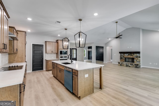 kitchen featuring a kitchen island with sink, vaulted ceiling, light hardwood / wood-style flooring, stainless steel appliances, and decorative light fixtures