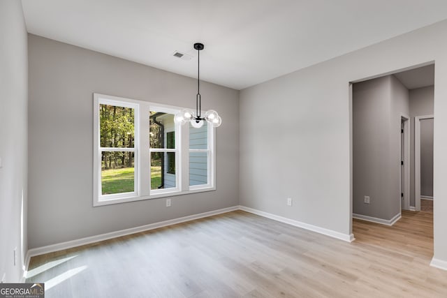 unfurnished dining area featuring a chandelier and light wood-type flooring