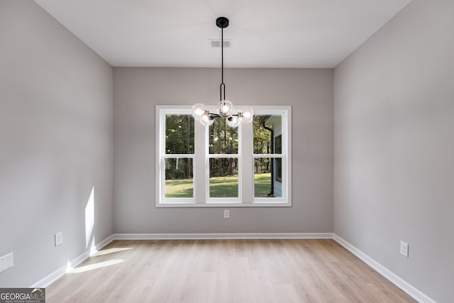 unfurnished dining area with a chandelier and light hardwood / wood-style floors