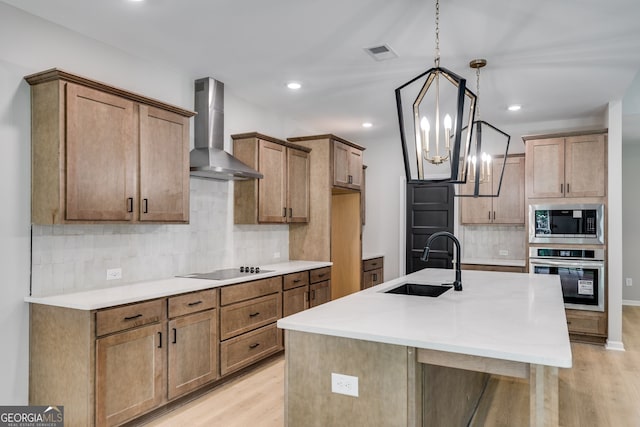 831 Banks Cir, Carrollton, GA 30116 - kitchen featuring stainless steel appliances, wall chimney range hood, a sink, light wood-style floors, and decorative backsplash