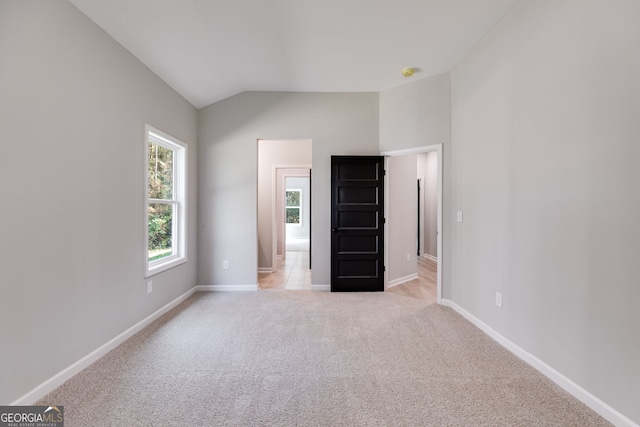 unfurnished bedroom featuring lofted ceiling and light carpet