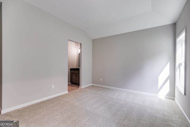 carpeted spare room with lofted ceiling