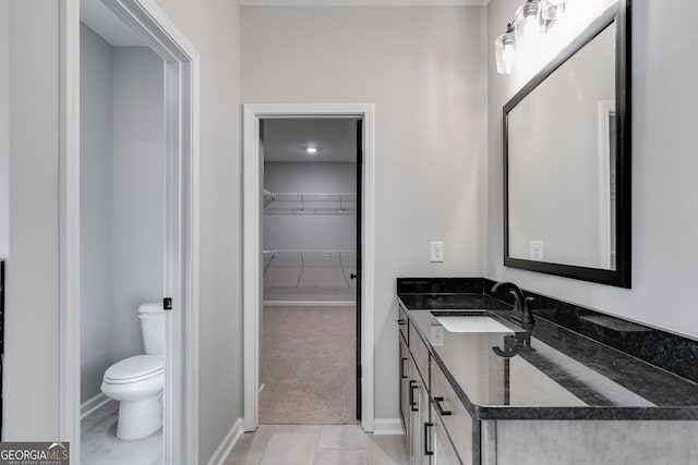 831 Banks Cir, Carrollton, GA 30116 - bathroom with vanity, a walk in closet, toilet, and baseboards