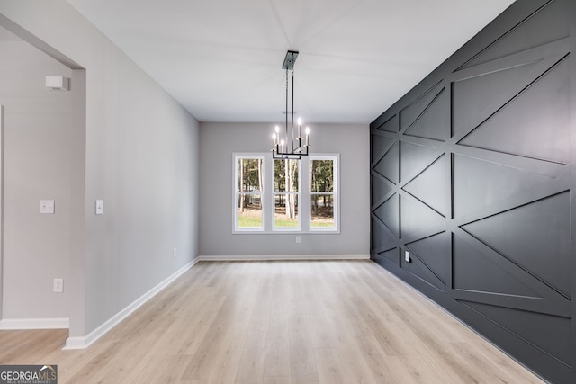 unfurnished dining area with light hardwood / wood-style floors and an inviting chandelier