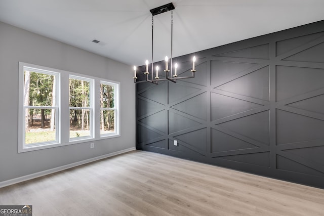 unfurnished dining area featuring an inviting chandelier and light wood-type flooring