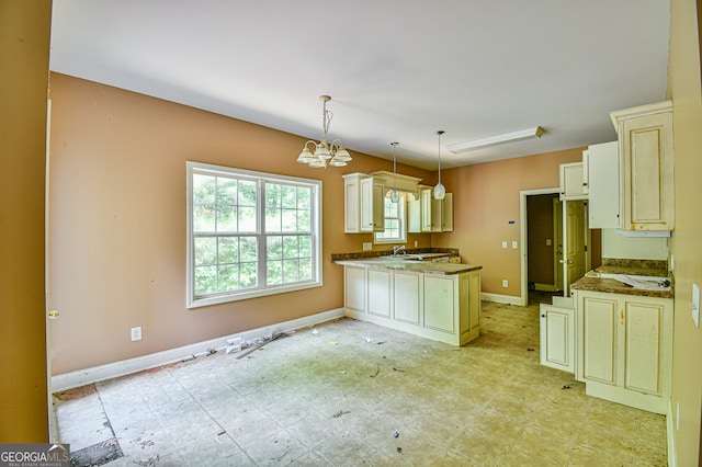 kitchen with kitchen peninsula, decorative light fixtures, light tile patterned floors, cream cabinets, and a notable chandelier