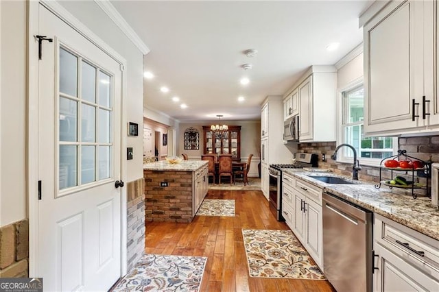 kitchen with light stone countertops, appliances with stainless steel finishes, white cabinetry, sink, and backsplash