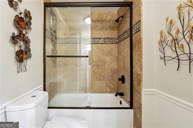 bathroom with combined bath / shower with glass door and toilet