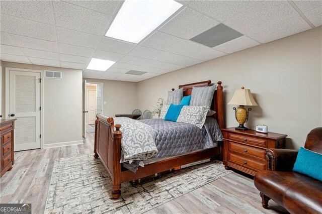 bedroom featuring light wood-type flooring and a drop ceiling