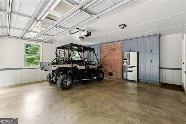 garage featuring stainless steel refrigerator with ice dispenser and a garage door opener