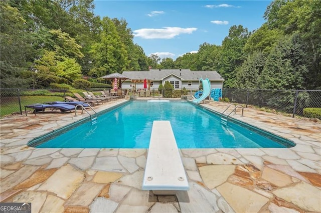 view of pool featuring a patio area, a diving board, and a water slide