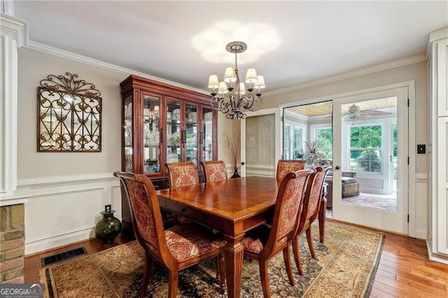 dining space featuring ornamental molding, light hardwood / wood-style floors, and a notable chandelier