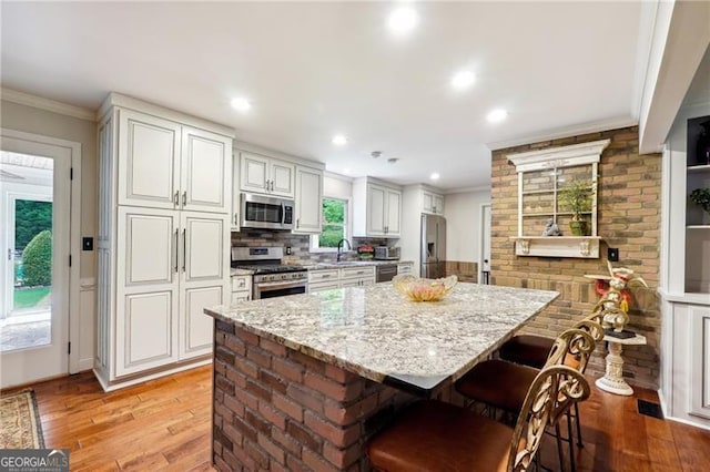 kitchen with light stone counters, a center island, stainless steel appliances, and a breakfast bar area