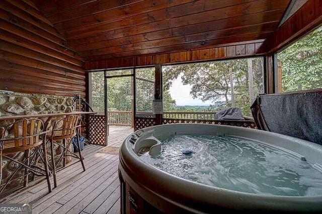 sunroom / solarium featuring a healthy amount of sunlight, vaulted ceiling, and a hot tub