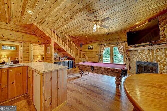 playroom featuring wood ceiling, a stone fireplace, light wood-type flooring, and pool table