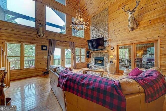 living room featuring a fireplace, light hardwood / wood-style flooring, wooden walls, and high vaulted ceiling