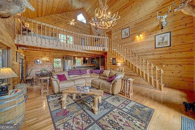 living room featuring a notable chandelier, light wood-type flooring, wood walls, wood ceiling, and high vaulted ceiling