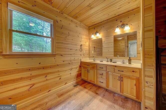 bathroom featuring dual vanity, wood walls, plenty of natural light, and hardwood / wood-style floors