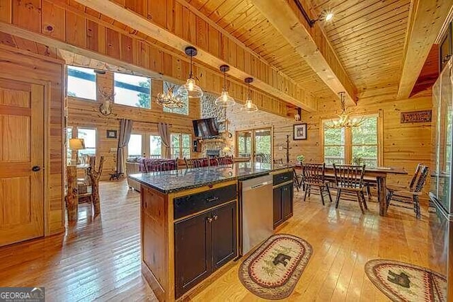 kitchen with dishwasher, hanging light fixtures, light wood-type flooring, a center island, and wood walls