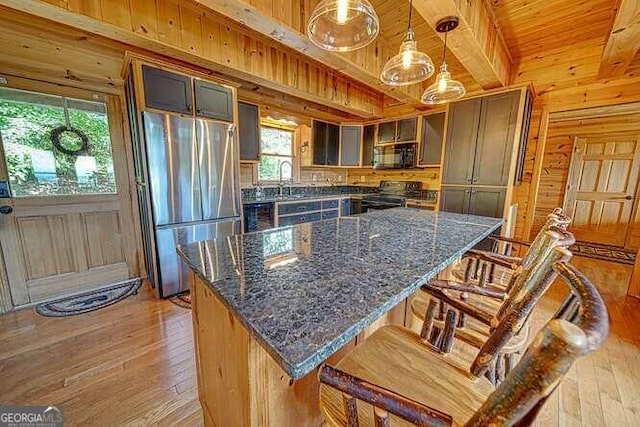 kitchen with light hardwood / wood-style floors, electric range, stainless steel refrigerator, and a healthy amount of sunlight