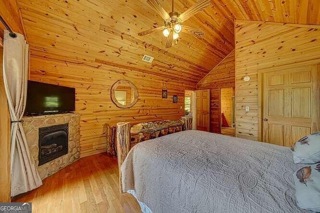 bedroom featuring wooden walls, wood ceiling, a fireplace, wood-type flooring, and vaulted ceiling