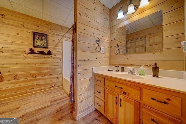 bathroom with hardwood / wood-style flooring, wood walls, and vanity