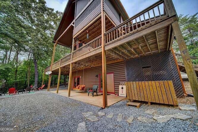 rear view of property with a wooden deck and a patio area