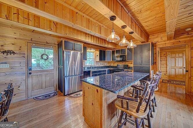 kitchen with wood walls, black appliances, and a wealth of natural light