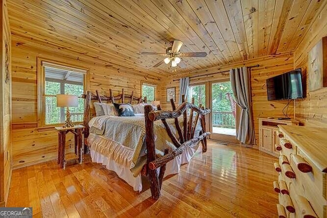 bedroom with light hardwood / wood-style flooring, wooden walls, access to exterior, ceiling fan, and wooden ceiling