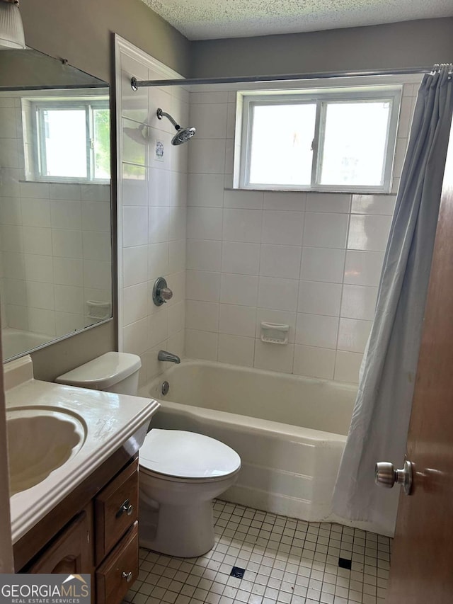 full bathroom featuring tile patterned flooring, shower / bath combo, toilet, vanity, and a textured ceiling